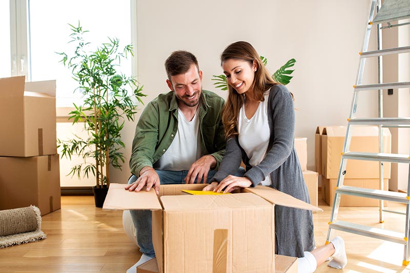 Couple surrounded by moving boxes before scheduling home inspection services 